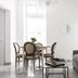 Carmelita Valletta living room with gray sofa, glass coffee table, and dining table in a bright white space.