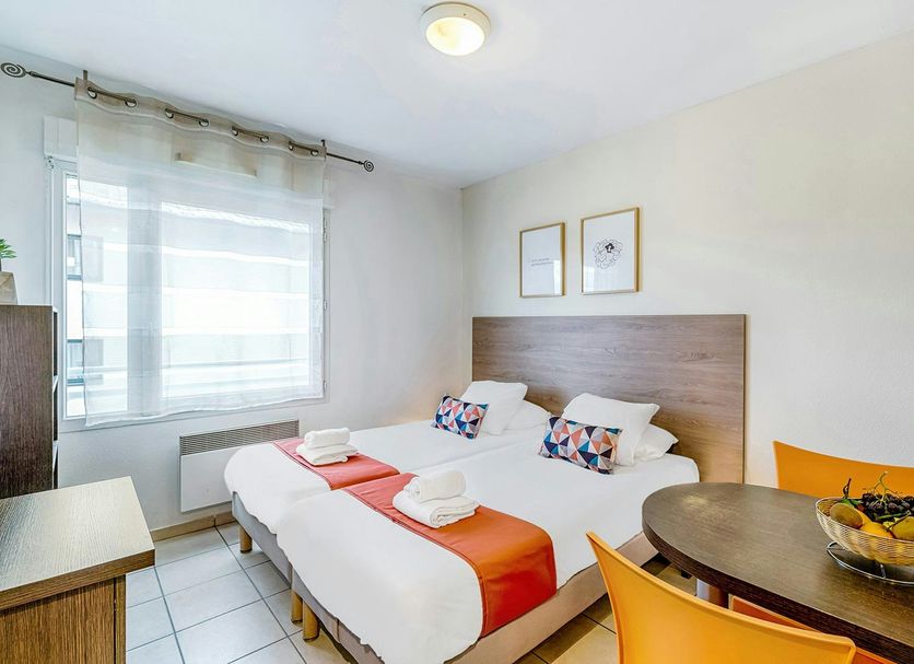 Appart'City Classic Thonon Les Bains room with twin beds, desk, window and small dining table