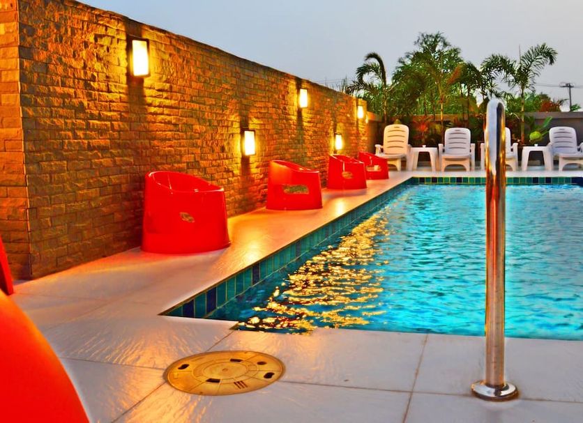 Dwella Suvarnabhumi Bangkok rooftop pool with red lounge chairs and brick wall lighting