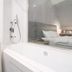 Amrise Hotel Kitchener Singapore bathroom with bathtub, shower and glass window to bedroom