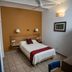 Parador San Agustin Oaxaca guest room with twin bed, warm accent wall, tile floor and ceiling fan