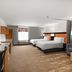 Home2 Suites by Hilton Alexandria guest room with two beds, sofa, TV, and window seat