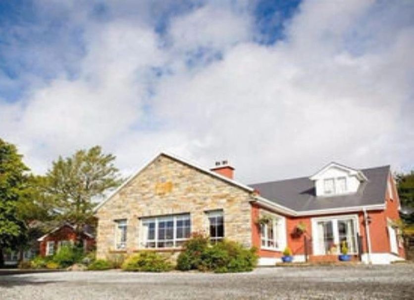 Ard na Breatha in Donegal, a stone and red hotel exterior with landscaped grounds under a cloudy sky