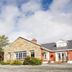 Ard na Breatha in Donegal, a stone and red hotel exterior with landscaped grounds under a cloudy sky