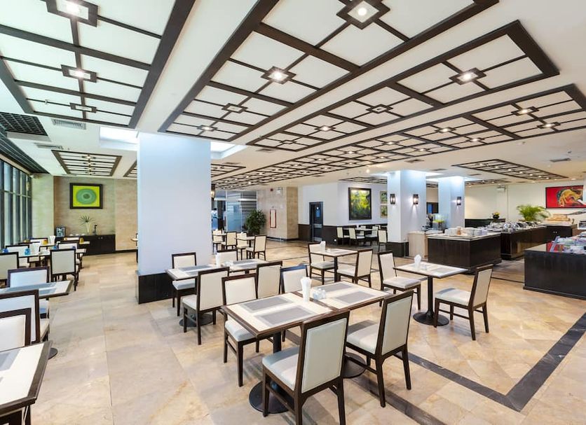 Pinnacle Lumpinee Park Hotel, Bangkok dining area with tables, chairs, buffet counter and geometric ceiling
