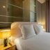 Makom Pereire in Paris bedroom with a neatly made bed, bedside lamp, and window with curtains
