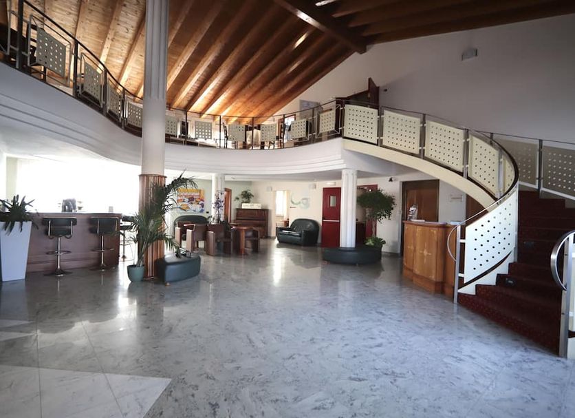 Hotel Riz B.B in San Genesio ed Uniti lobby with curved staircase and high wood-beamed ceiling