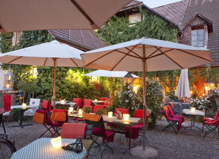 Outdoor terrace at Landgasthof Bären in Madiswil with umbrellas, red chairs and tables