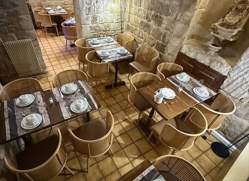 New Hôtel Gare Du Nord in Paris dining area with wicker chairs and set tables in a stone-walled room