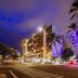 Castle @ Waikiki Grand in Honolulu at night with palm trees and city street view