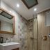 Angela in Kos bathroom with walk-in glass shower, wall-mounted toilet and wood vanity