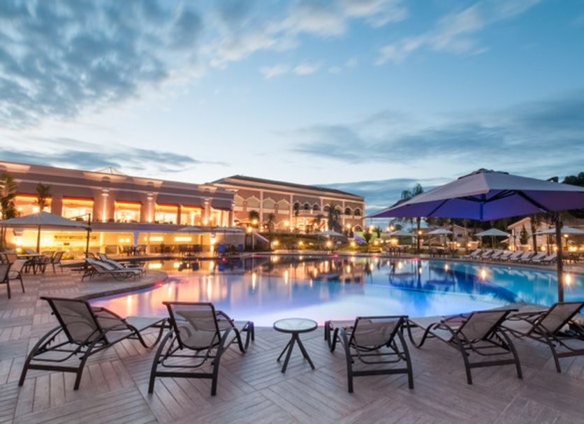 Wish Foz do Iguaçu poolside lounge chairs by a lit outdoor pool at dusk in Foz do Iguaçu