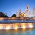 NH Madrid Nacional in Madrid with a lit fountain and ornate historic building at dusk