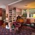 Hearthstone Elegant Lodge by the River in Kamiah: cozy pink lounge with bookshelves, piano, and floral carpet