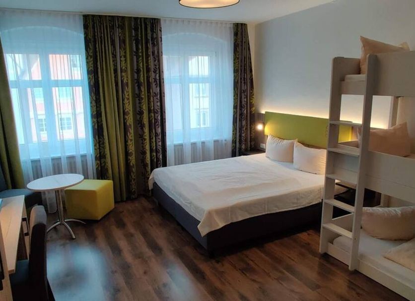 Hotel Goldene Traube in Günzburg room with double bed, bunk bed, desk and window curtains