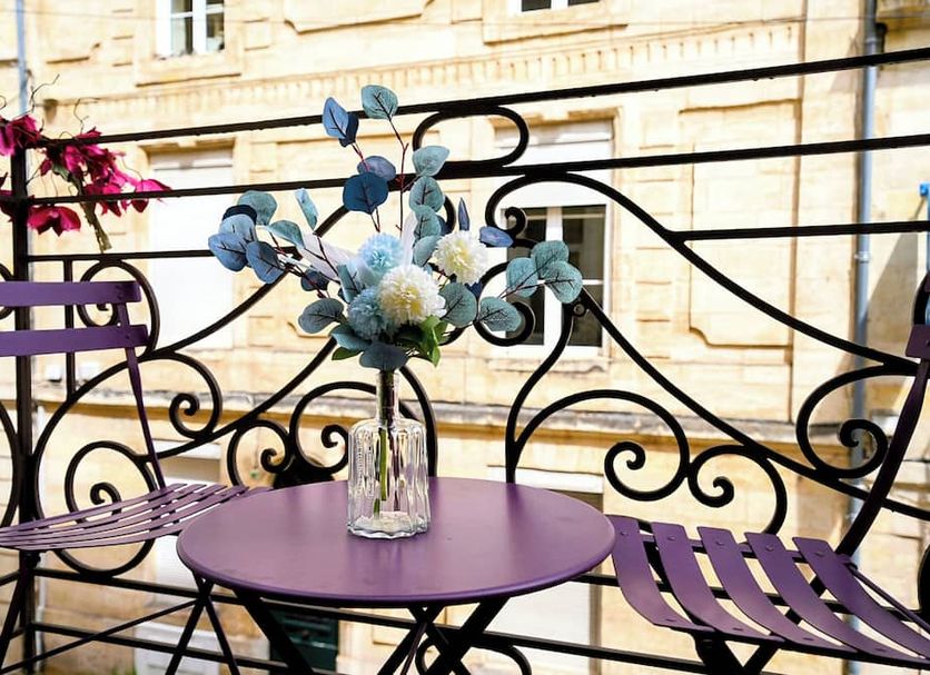 Au Coeur de Bordeaux B&B balcony with purple table, chairs and flower vase in Bordeaux