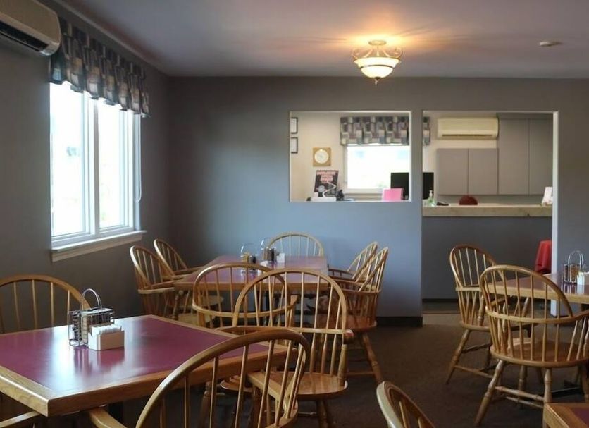 Coastal Inn - Kingfisher in Digby dining area with wooden tables, wicker chairs, and serving counter