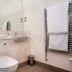 The Lodge At Craigielaw bathroom with wall-mounted toilet, sink, mirror, towel rail and wood door in Gullane