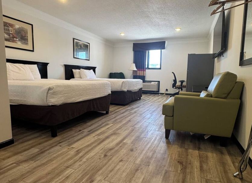 Home Suites Thief River Falls guest room with two beds, armchair, and window view