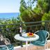 Hotel Loukas Vrachos balcony with sea view, table, chairs and fruit bowl in Vrachos