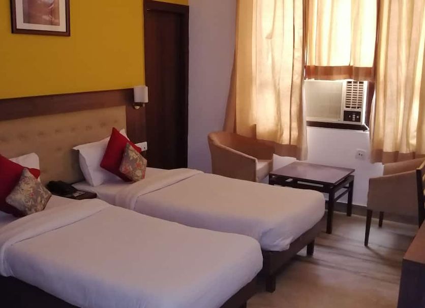 Hotel Inn Tawang New Delhi twin room with two single beds, desk, chairs, and window AC