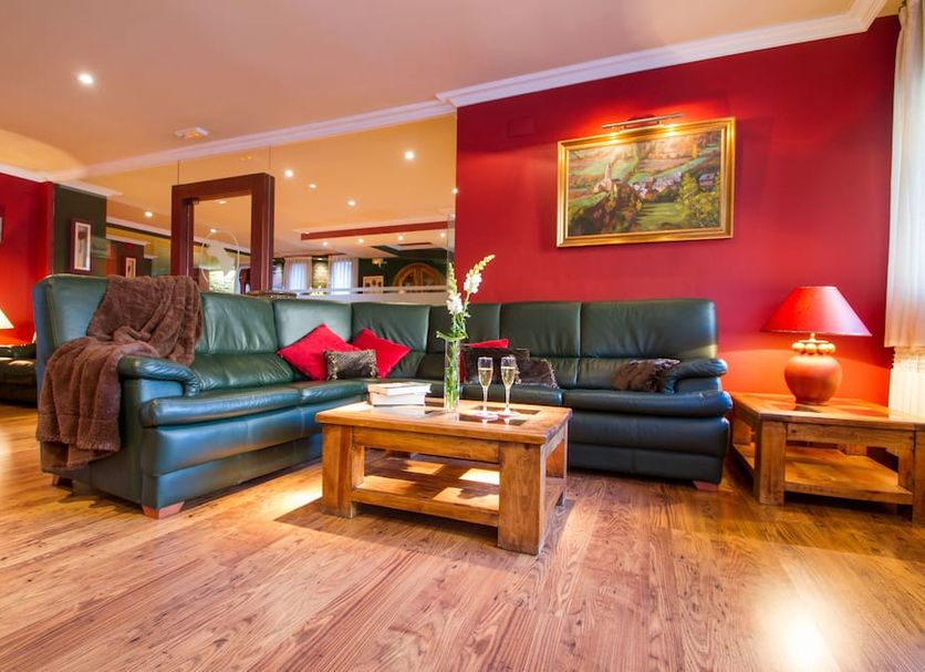 Gran Chalet Hotel in Viella living room with leather sofas, coffee table, and warm red walls