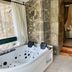 Palacio Torre de Ruesga in Valle: stone bathroom with a corner jetted tub beside a bedroom doorway
