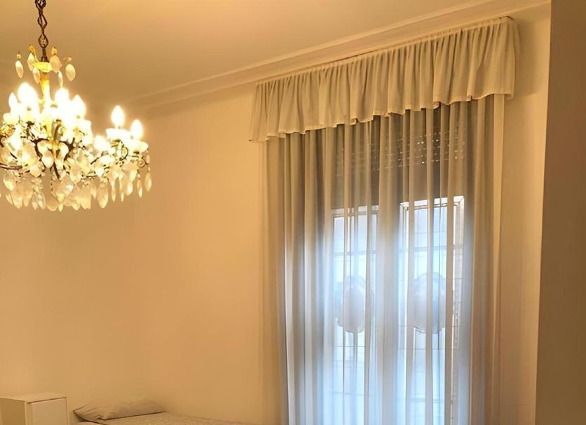 City Center Best Hostel in Milan room with chandelier, two single beds and sheer-curtained window