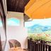 Balcony at Hotel Schauinsland in Bad Peterstal-Griesbach with wicker chairs, orange umbrella, and hillside view