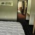 Lakewood Inn & Suites in Dowagiac guest room with bed, lamp and hallway view