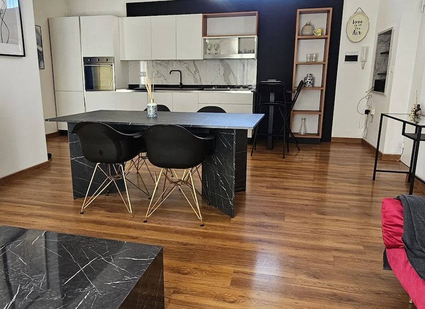 Flamingo B&B in Pompei kitchen and dining area with island, black chairs, and wood flooring