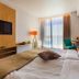 Marina Burgas Hotel room in Burgas with a bed, wall-mounted TV, desk, and large window with curtains