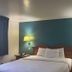 Motel 6 Portland, IN guest room with king bed, teal accent wall, bedside lamps and nightstands