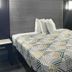 Motel 6 Meridian Ms guest room with patterned bed, bedside table and wall light in Meridian