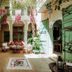 Riad Dar Ayur Marrakech courtyard with palm trees, seating area, and green shutters