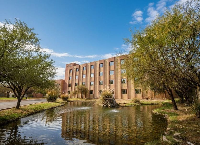 Hotel Agua Del Desierto in Calama with a pond and landscaped trees outside the hotel