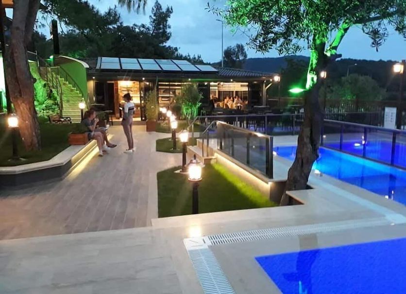 The Sarigerme Inn in Sarigerme with illuminated outdoor pool and deck at dusk
