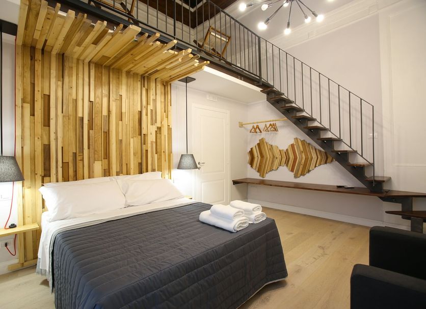 The Dante House in Naples, loft-style room with double bed, staircase, and wood accent wall