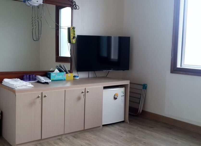 Minjoonggak, Seogwipo: room with TV, mini fridge, cabinet, window and wall-mounted fan