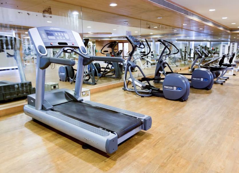 Lalco Residency in Mumbai gym with treadmill, exercise bikes and mirrors on a wood floor
