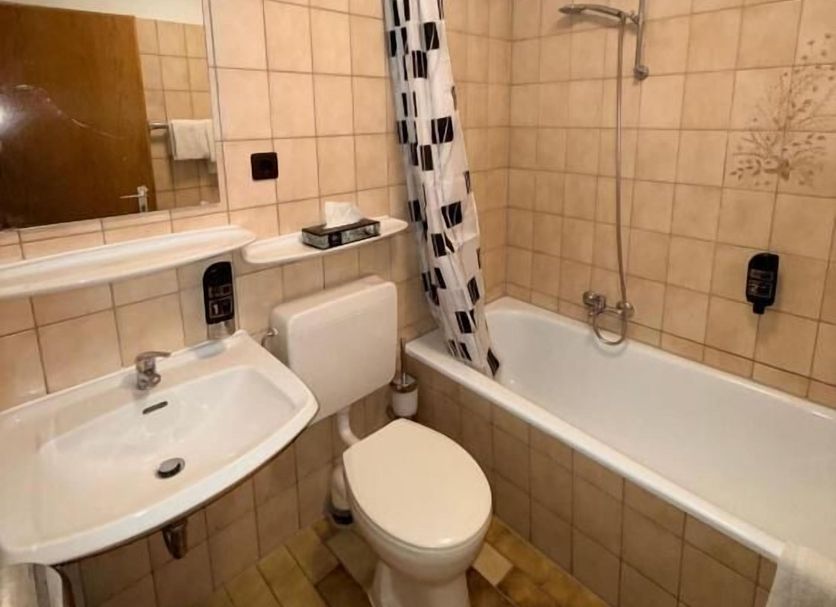 Yeti City Hotel Saarbrücken bathroom with bathtub, shower, sink and toilet in Saarbruecken