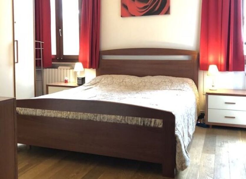 Casa Perlar Verona bedroom with wooden bed, red curtains, and rose wall art