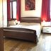 Casa Perlar Verona bedroom with wooden bed, red curtains, and rose wall art