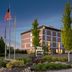 Home2 Suites by Hilton Idaho Falls exterior at dusk with landscaped entrance and flagpoles