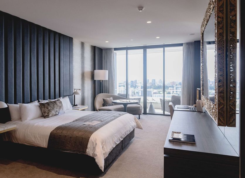 Emporium Hotel South Bank in Brisbane room with king bed, city view balcony doors, and lounge chair