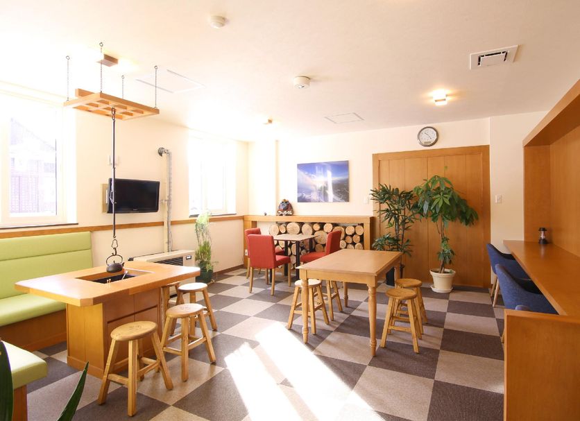 Lodge Koropokkuru in Niseko breakfast room with tables, stools, and checkered flooring