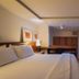 Hotel Habitare in Nova Friburgo guest room with bed, desk, TV and warm lighting