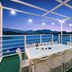 Onda D'oro Hostel Yeosu rooftop terrace with ocean view, dining table, and string lights at dusk