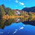 Hostal de la Laguna in Ushuaia beside a calm lake reflecting autumn trees and mountains