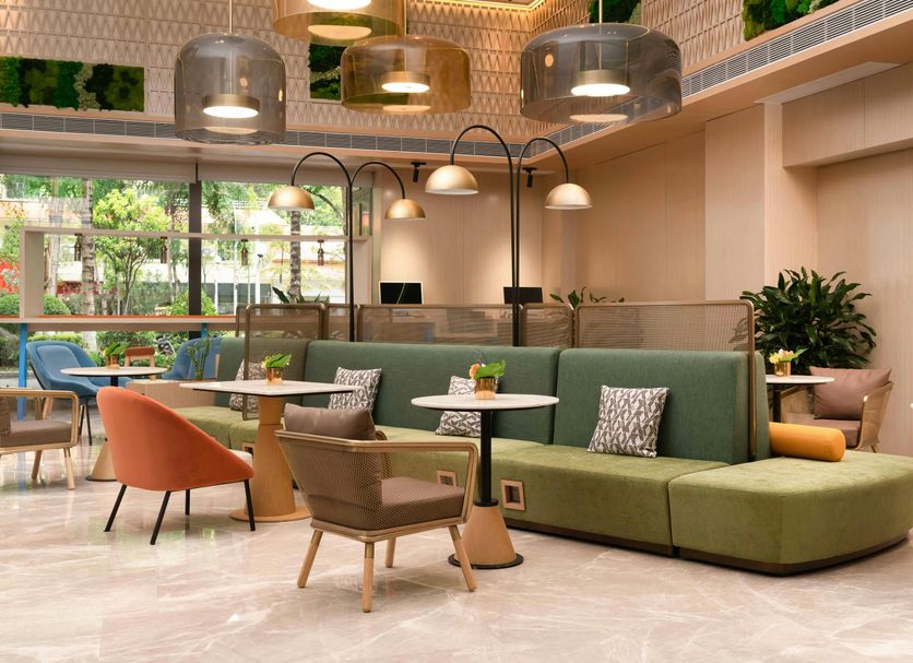 Home2 Suites by Hilton Xishuangbanna Jinghong lobby with green sectional seating and lounge chairs